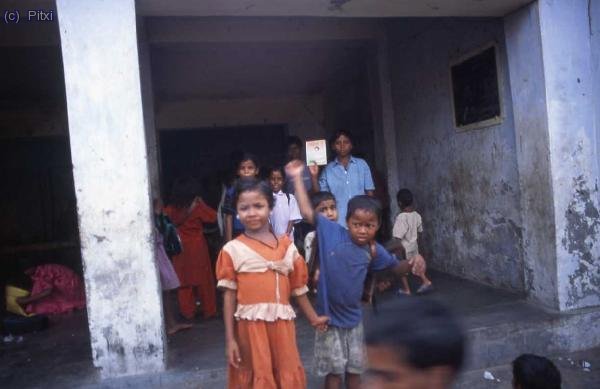Escuela en Varanasi (lo que se ve al fondo es el aula). Uno de los ni&ntilde;os muestra orgulloso su cartilla de escolarizaci&oacute;n