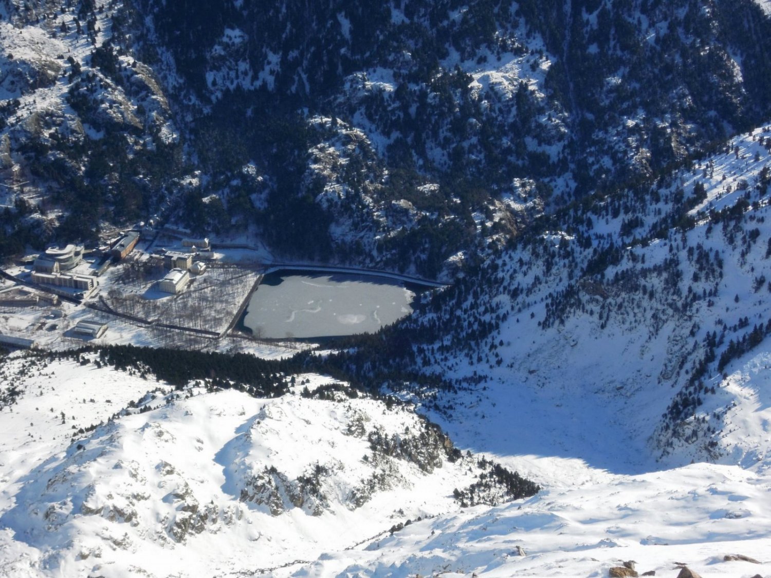 Des de el cim, molt avall, veiem el Balneario de Panticosa. Es veu clarament el promontori que baixant passarem per l