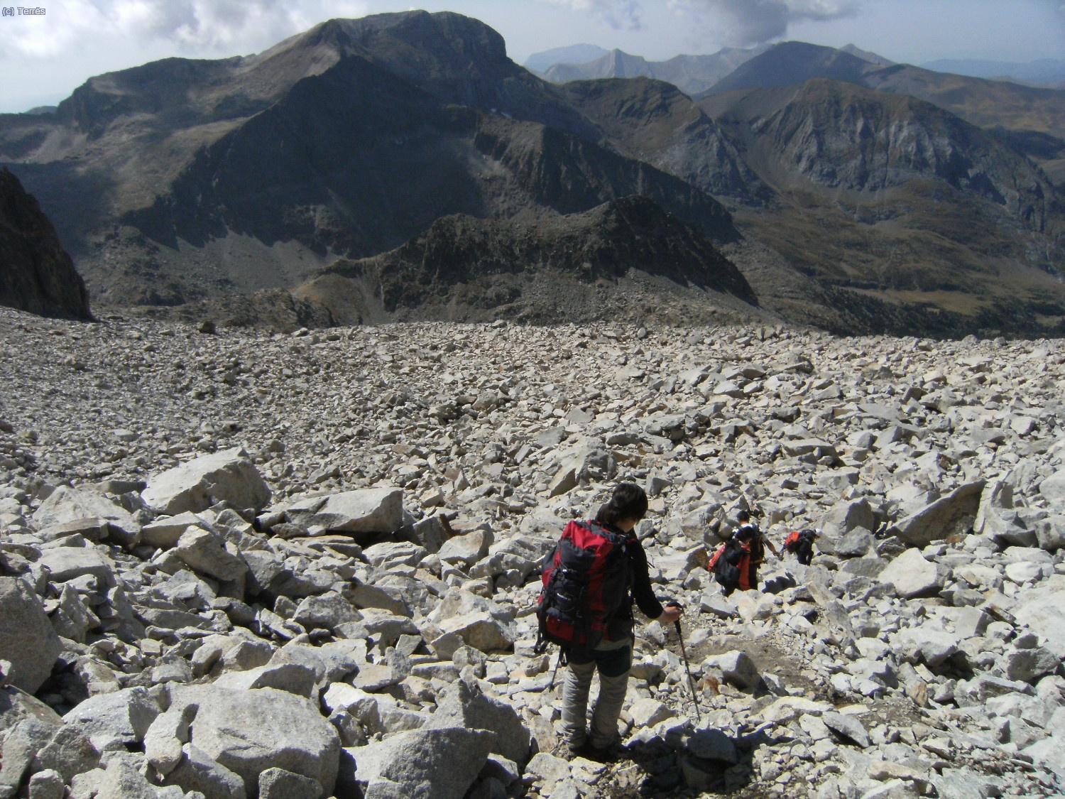 Delante Nuria bajando por el caos de rocas, al fondo el Pico de Vallibierna